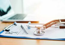 Stethoscope on a prescription form beside a pen and laptop