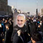 Iran Strikes Ignite War-Powers Showdown Qasem Soleimani portrait held aloft in a crowded street gathering