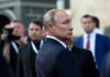 Fuel Relief or Moscow Payday? Vladimir Putin in a dark suit looking over his shoulder amid a crowd