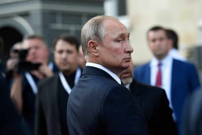 Vladimir Putin in a dark suit looking over his shoulder amid a crowd