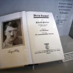 Open historical book on display with portrait and title page