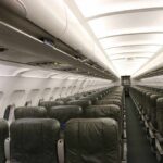 Airplane cabin with empty rows of economy seats and overhead bins