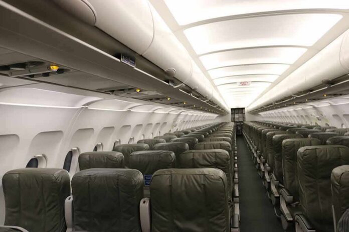Airplane cabin with empty rows of economy seats and overhead bins