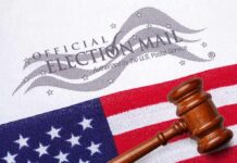 Gavel on U.S. flag beside official election mail envelope