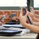Meta Slammed: Teen Time-Locks Incoming students' hands using smartphones at a classroom table