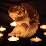 angel statue surrounded by lit candles