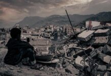 UN Slams ‘Reckless’ Strikes – Iran’s Proxy Escalates Boy sitting on rubble overlooking a devastated city