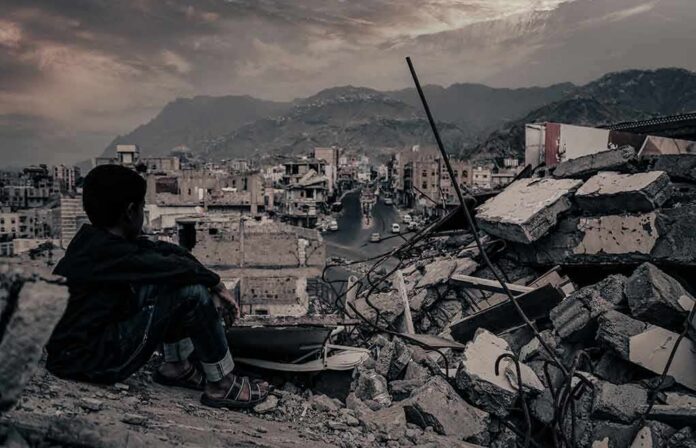 Boy sitting on rubble overlooking a devastated city