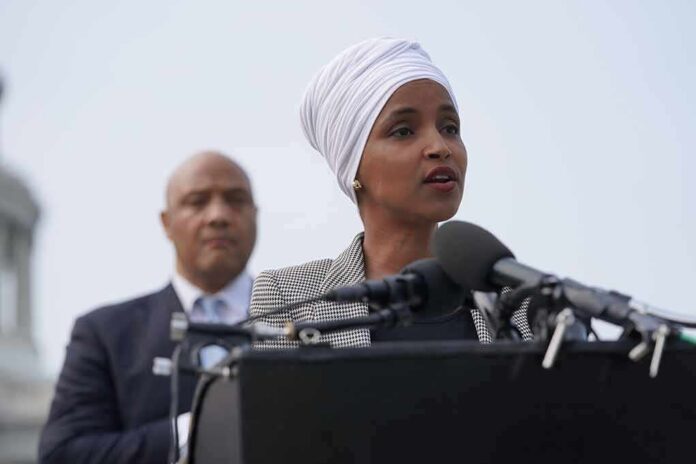 Ilhan Omar speaking at a podium with André Carson standing behind
