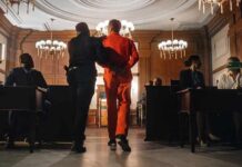 Probation Fail: Robber Strikes Again Prisoner in orange jumpsuit escorted by officer in a courtroom