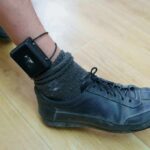 ankle with electronic monitoring bracelet and black shoe
