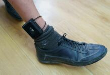 ankle with electronic monitoring bracelet and black shoe