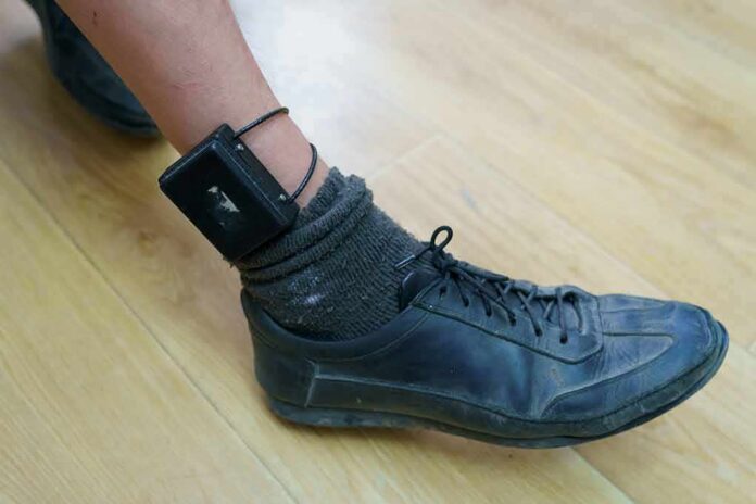 ankle with electronic monitoring bracelet and black shoe