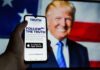 Smartphone showing Truth Social app screen with Donald Trump on a U.S. flag backdrop