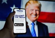 Smartphone showing Truth Social app screen with Donald Trump on a U.S. flag backdrop