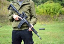 person holding a black rifle outdoors