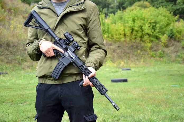 person holding a black rifle outdoors