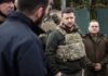 man in tactical vest standing with group outdoors