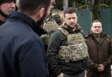 man in tactical vest standing with group outdoors