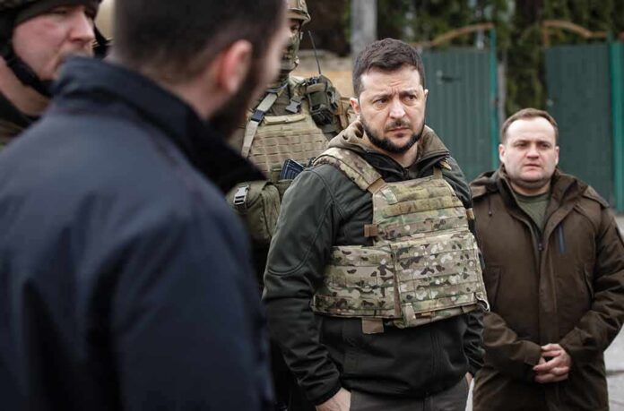 man in tactical vest standing with group outdoors