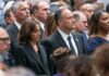 Spouse Doubt Jolts Harris 2028 Hopes Group of people standing at a solemn ceremony
