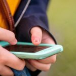 Hands holding a smartphone with a mint-green case