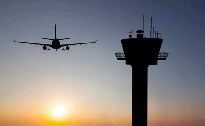 shutterstock_350063216 Airplane approaching runway near airport control tower at sunset