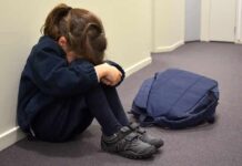 Norway’s Power Play: Seized Over Spanking Fears Child sitting on hallway floor with head down beside backpack