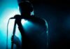 Singer silhouette holding a microphone on a dark stage