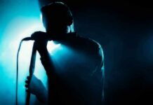 Singer silhouette holding a microphone on a dark stage