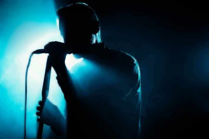 Singer silhouette holding a microphone on a dark stage