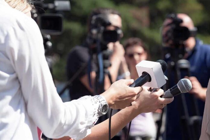 Reporters hold microphones during an outdoor press interview