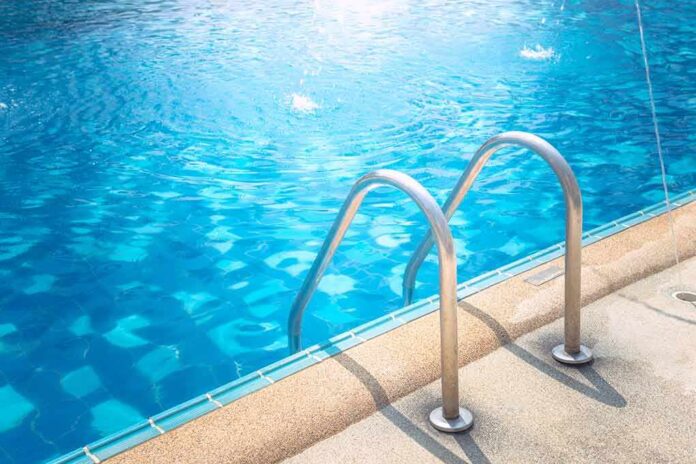 shutterstock_533928457 Swimming pool ladder by clear blue water