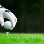 Golf glove placing ball on tee