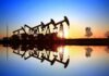 Oil pumpjacks at sunset reflected in still water