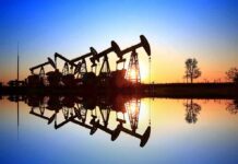 Oil pumpjacks at sunset reflected in still water