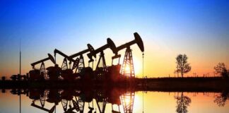 Oil pumpjacks at sunset reflected in still water
