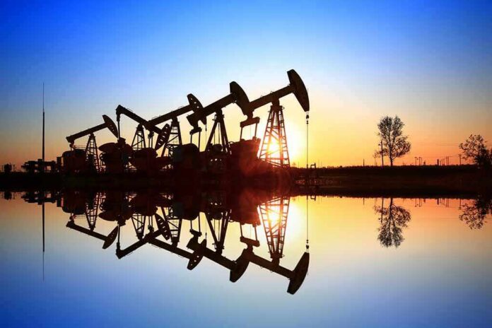 Oil pumpjacks at sunset reflected in still water